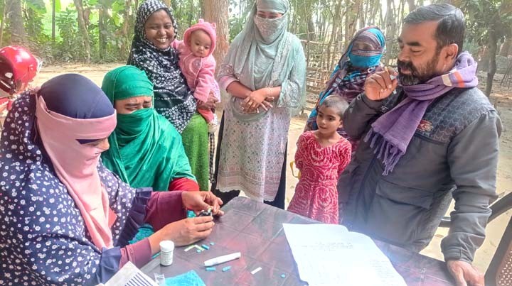 A staff of BASCO Foundation is checking sugar level to a woman.
